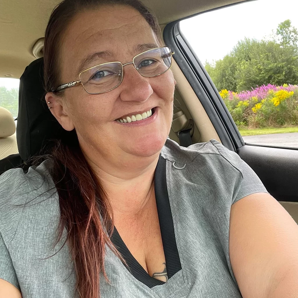 Smiling woman with glasses sitting in a car.