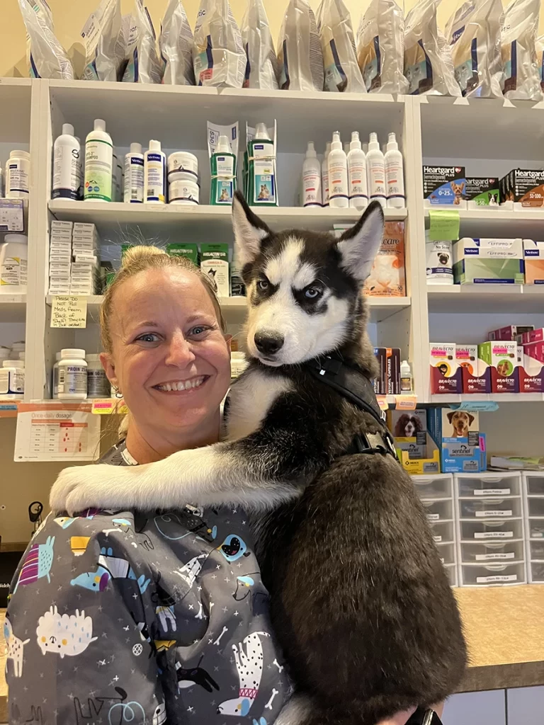 Woman in a veterinary clinic holding a husky puppy.